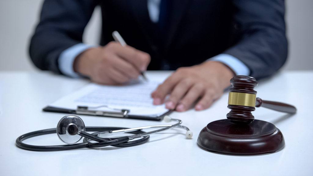 Judge signing wrongful death claim, banging gavel near stethoscope