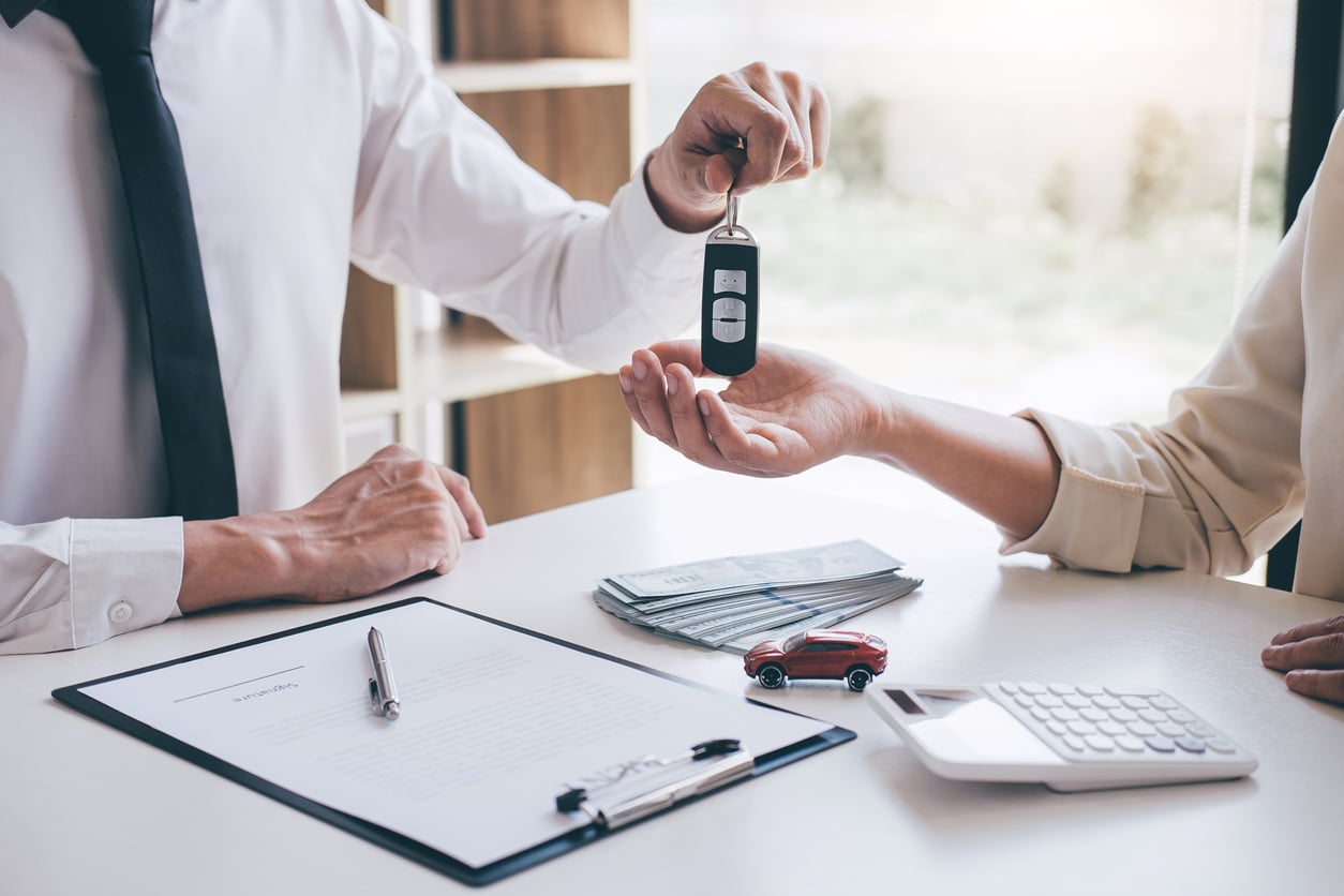 Car rent agent manager holding key of a car giving to woman
