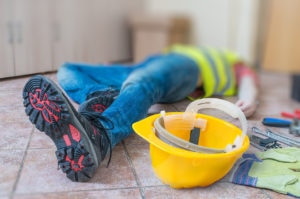 Leg and yellow helmet of injured lying worker at work.