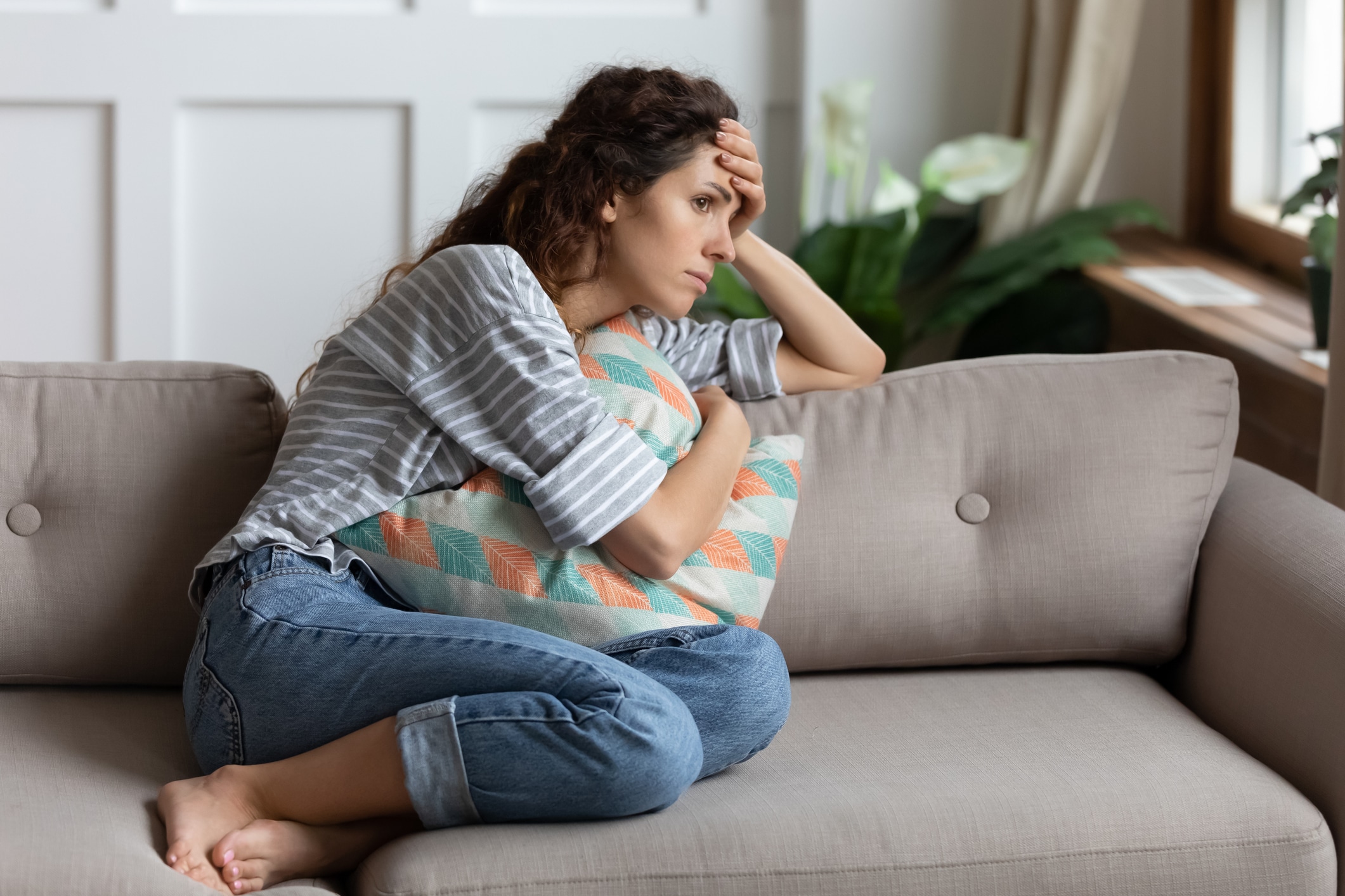 A woman looking worried on her couch.