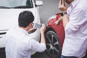 Two drivers collecting evidence after a car accident. 