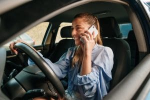 A young woman talking on the phone while driving.