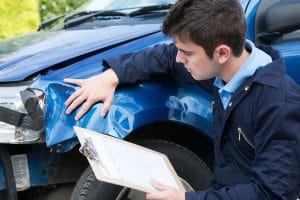 An auto shop worker inspecting damage to a vehicle. 
