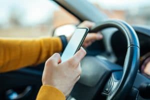 A person holding their cell phone while driving. 
