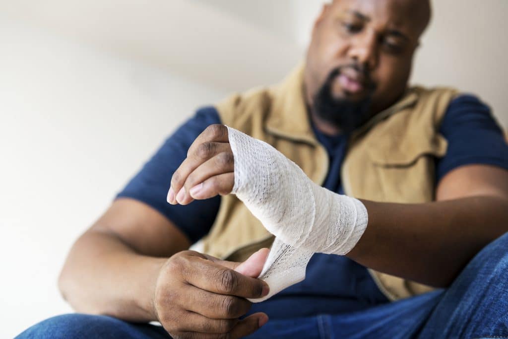 A man wrapping a bandage around his injured hand.