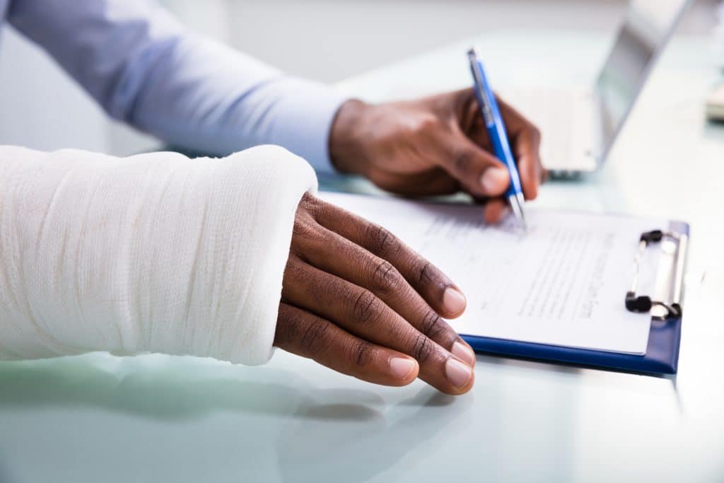 A man filling out an insurance form after suffering an injury in a truck accident.