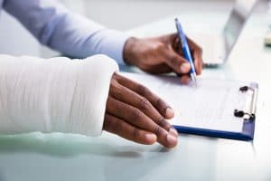 A man filling out an insurance form after suffering an injury in a truck accident.