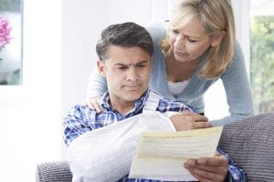 An injured man looking at his medical bills with his wife.