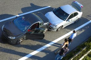 People standing outside their cars after an accident on the interstate.