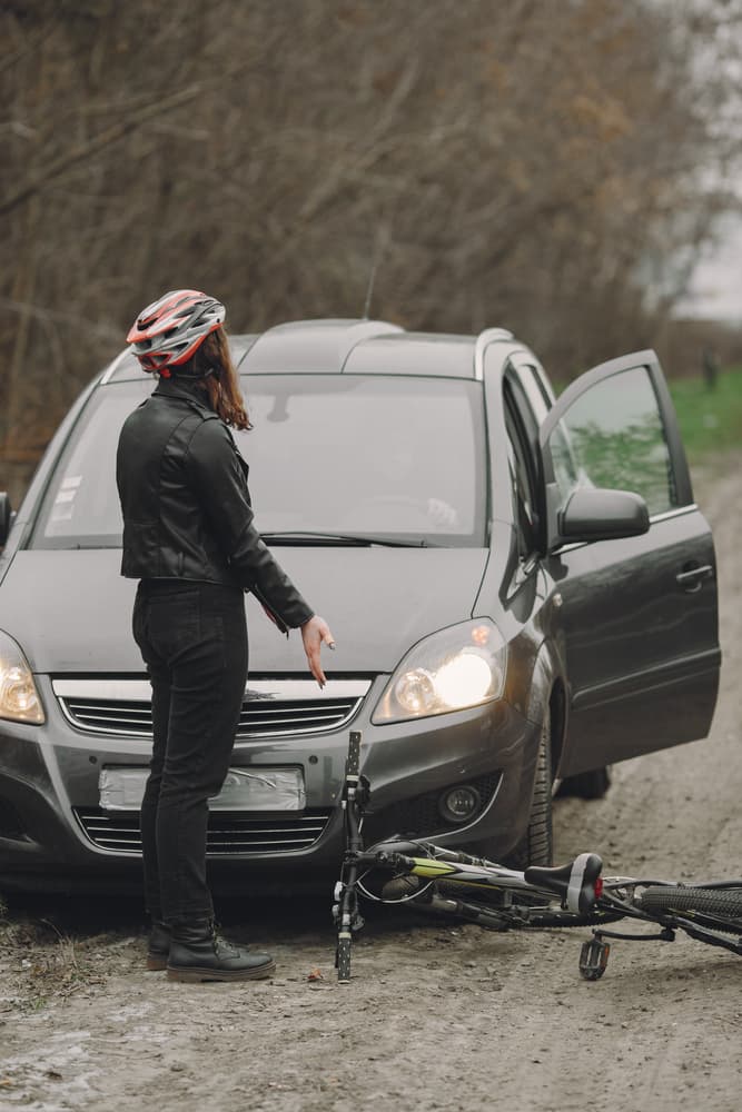 Woman in helmet involved in car crash. Tense scene as people argue over the accident, highlighting road safety and conflict.