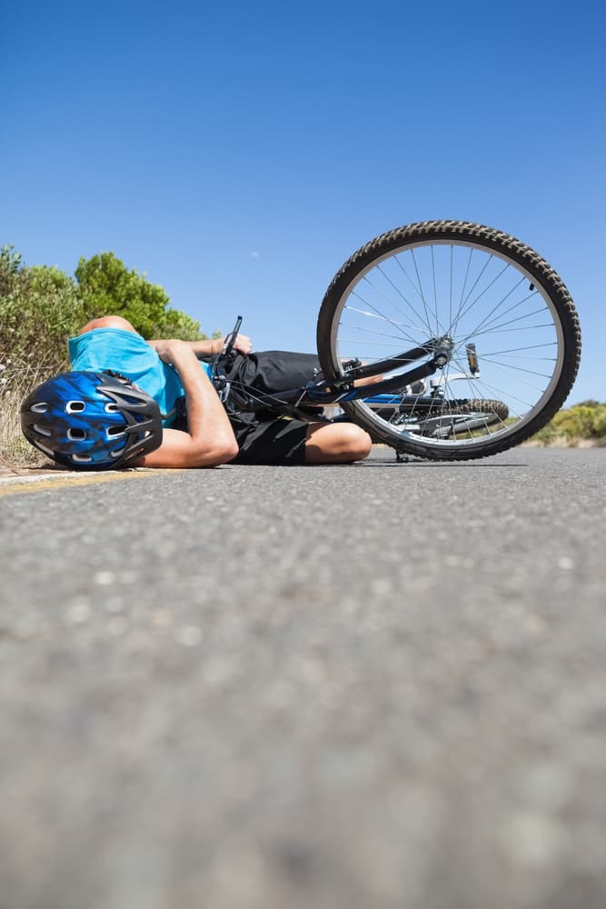 Cyclist down on the sunlit road in Waco, Texas, following an unfortunate accident.