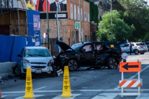 Two cars severely damaged after a crash on a residential area in San Antonio, with police and safety cones in place.