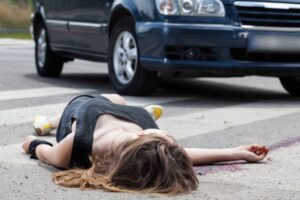 A person lying on the street after being hit by a car, depicting a pedestrian accident scene.