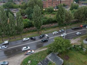 Overhead shot of several cars involved in a collision on a damp street, with police attending.