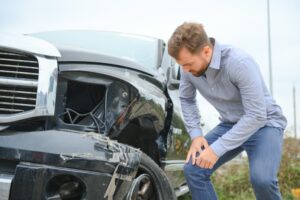 After a car accident, a regretful man assesses the damage caused, reflecting on the aftermath of the car wreck.