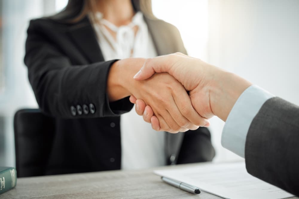 How can I assist? Image of two lawyers warmly shaking hands.