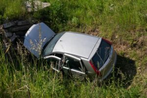 Discarded and damaged car in a rural field, reflecting abandonment and deterioration.