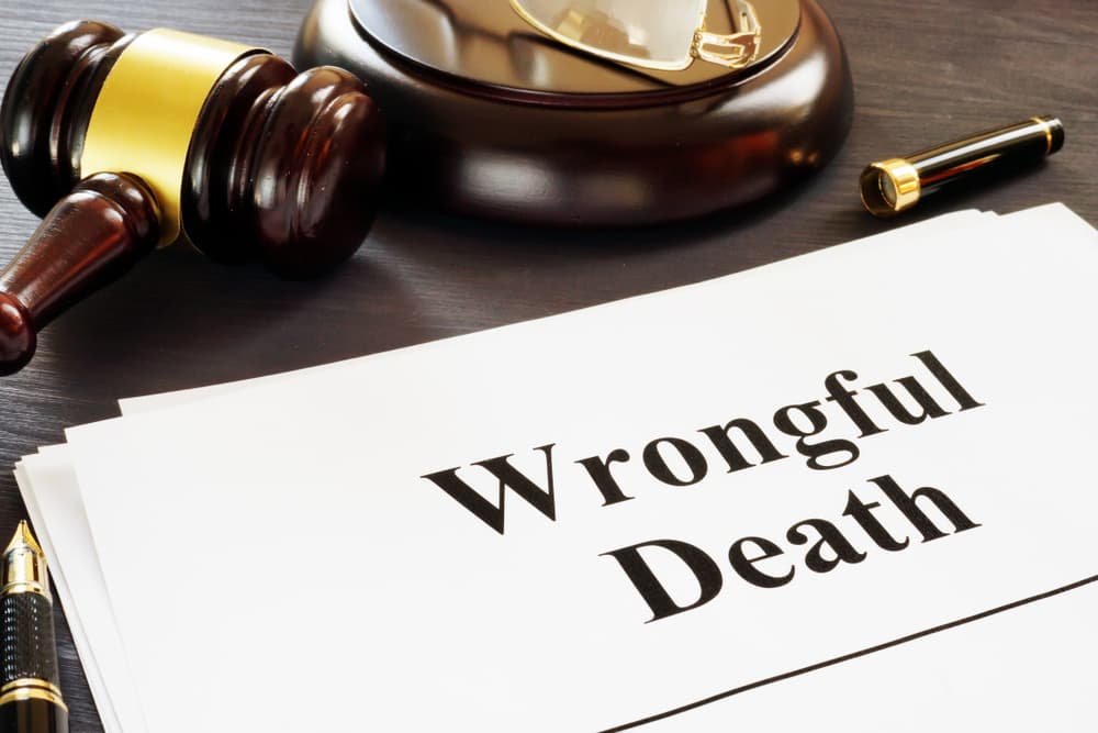 Documents titled "Wrongful Death" with a judge's gavel and a fountain pen on a dark wooden surface.