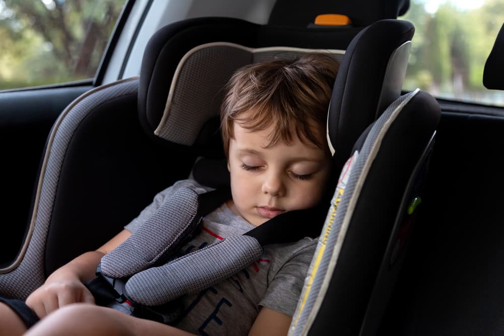 A small kid is asleep in a car seat, showing how to follow Texas's car seat rules safely.