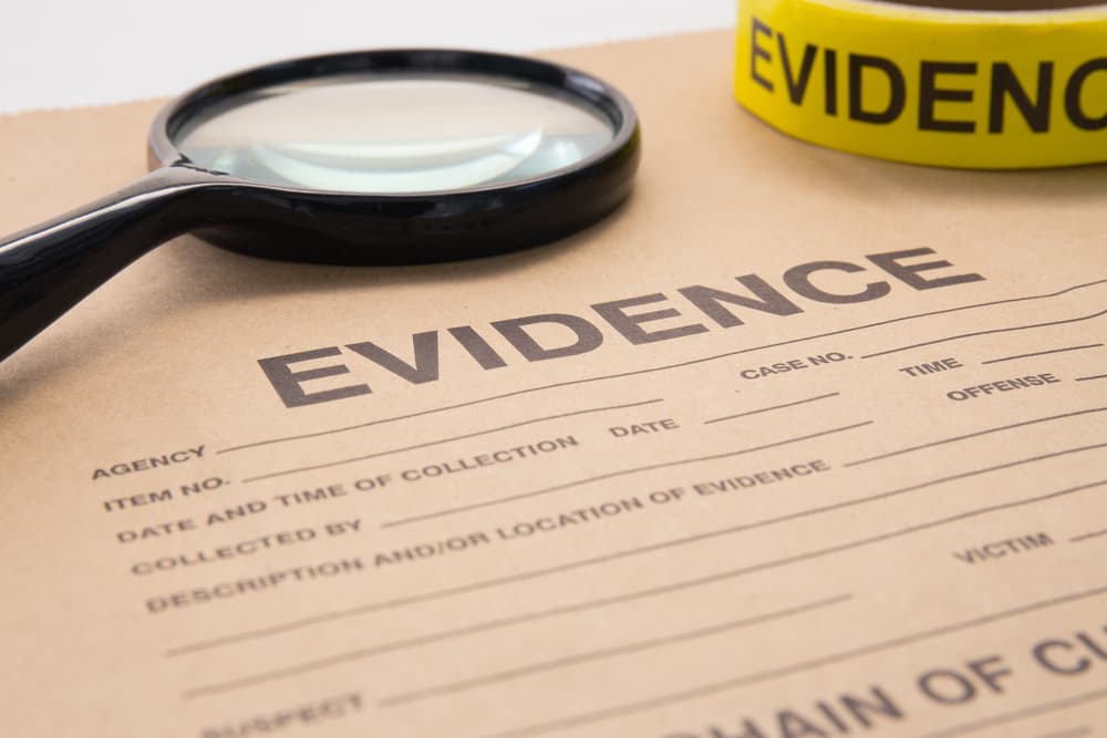 Close-up of evidence collection form with magnifying glass and yellow evidence tape for criminal investigation.