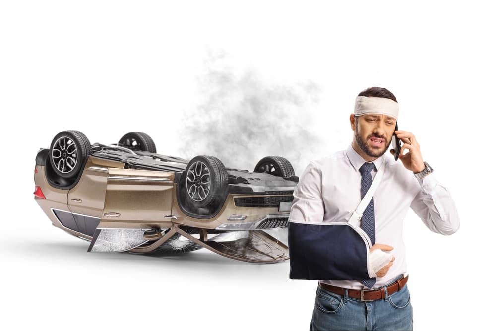Man injured in car accident makes emergency call for roadside assistance, isolated on white background.