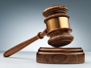 Wooden judge's gavel and soundboard on a blue background, angled perspective view.