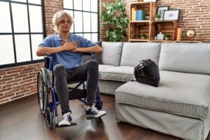 Young man in wheelchair, smiling with closed eyes and grateful gesture, symbolizing resilience and gratitude after motorcycle accident.