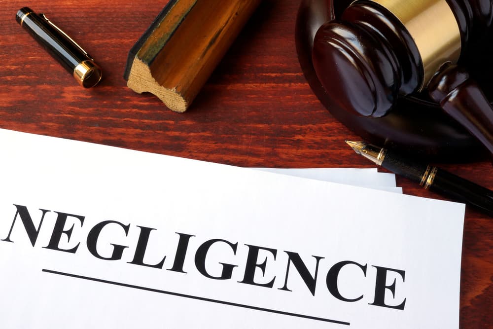 Document labeled "Negligence" on a wooden desk next to a judge's gavel and fountain pen, symbolizing legal action in personal injury or accident claims.