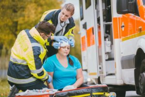 Emergency medics attend to head wound of injured woman following an accident.