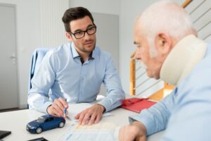 A personal injury lawyer meets with a client wearing a neck brace for consultation.