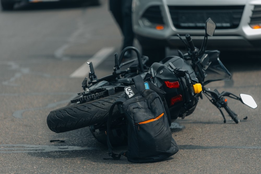 Motorcycle lying on the road next to a car, illustrating common causes of motorcycle accidents in Killeen