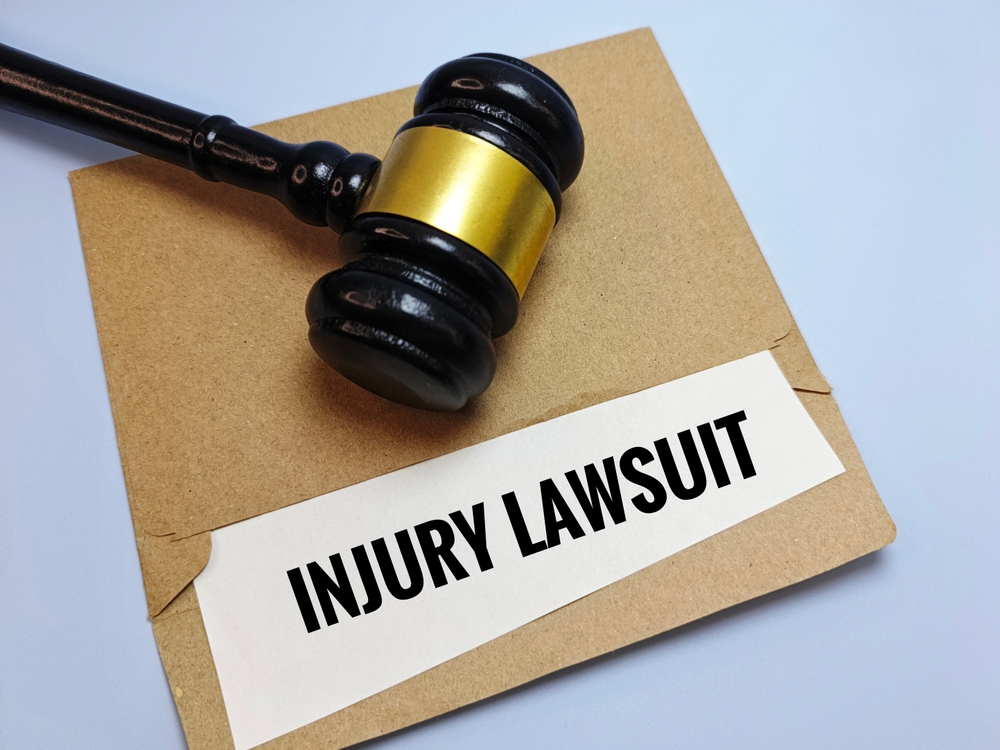 Injury Lawsuit Documents in Brown Envelope with Wooden Judge Gavel on Table &ndash; Legal Case Filing, Personal Injury Claim, Court Law Concept.